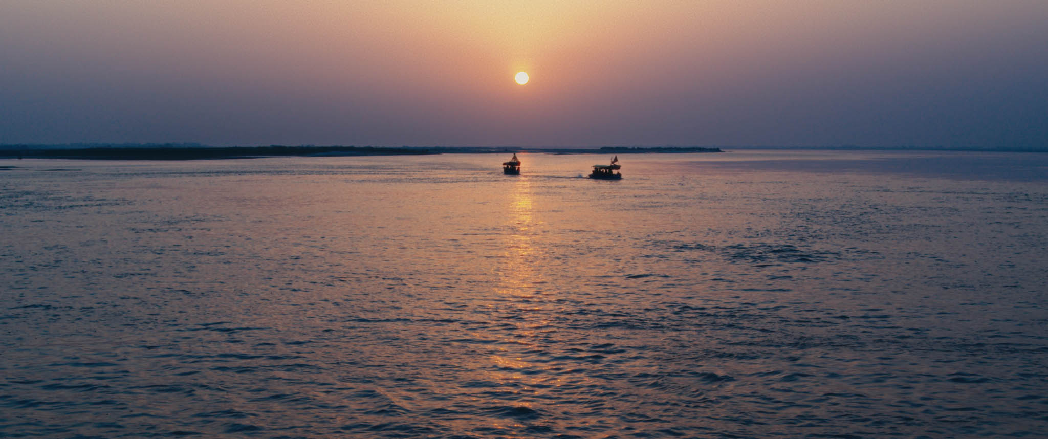 Sunset over water wit 2 boats in