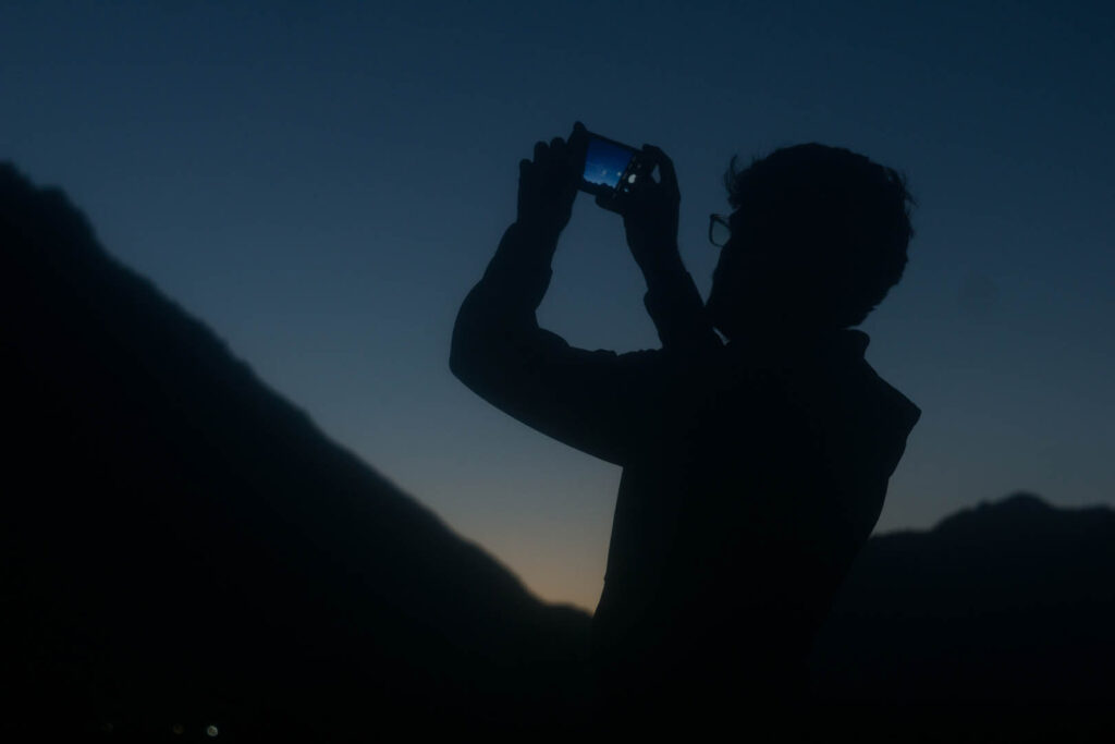 silhouette of man taking a picture of the night sky